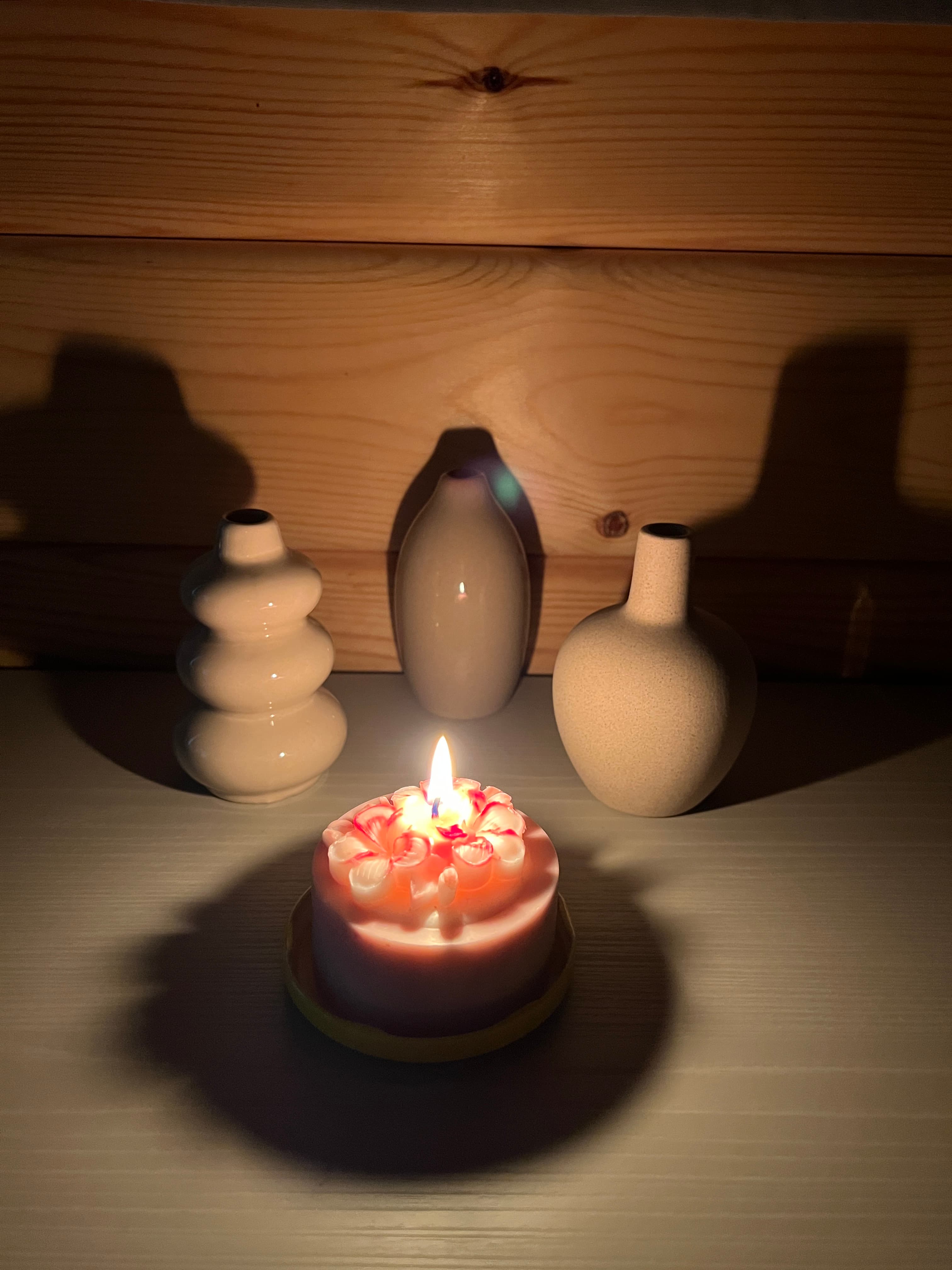 A customer’s lit candle among ceramic vases
